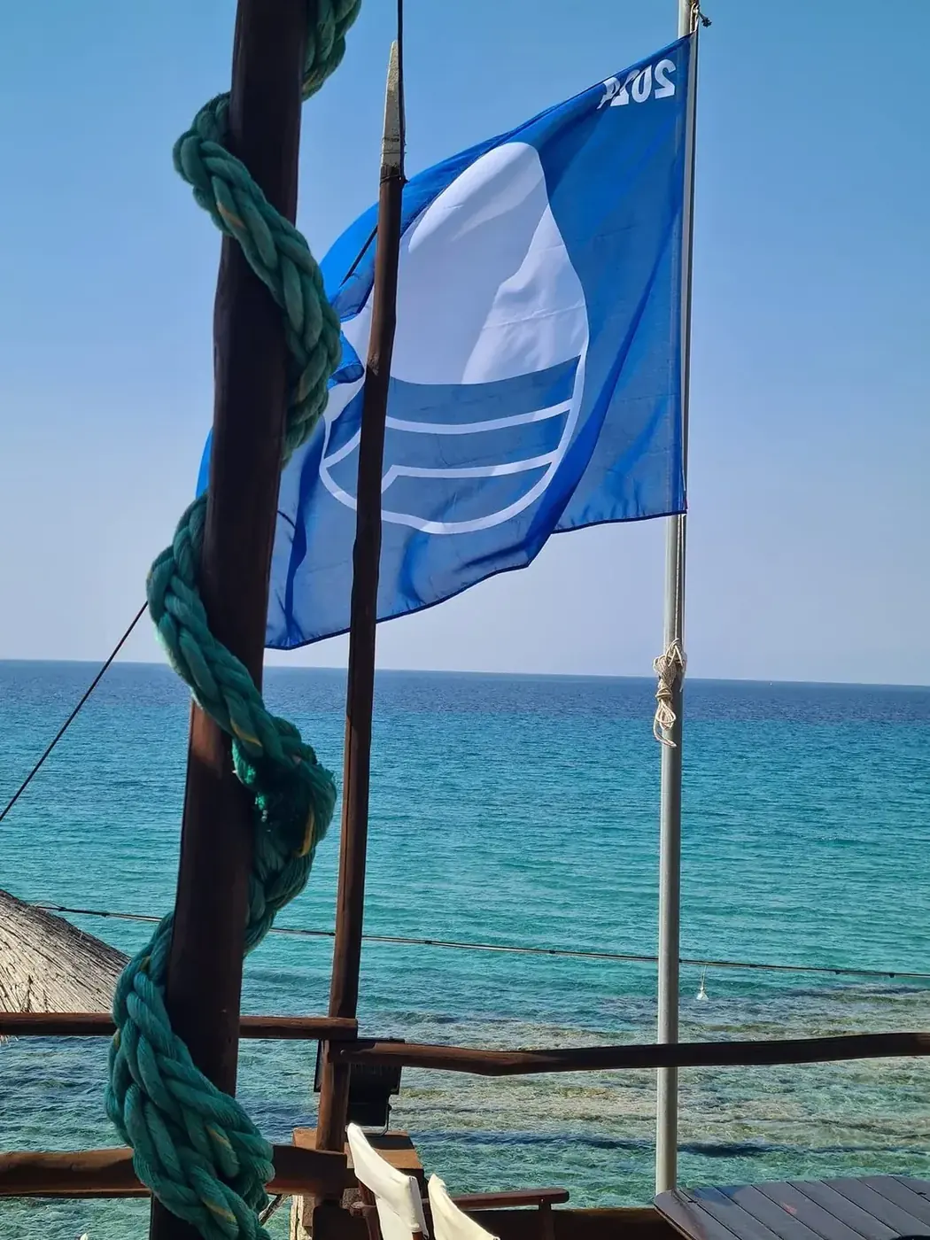 Blue Flag flying over the clear turquoise sea at Kudu's beach